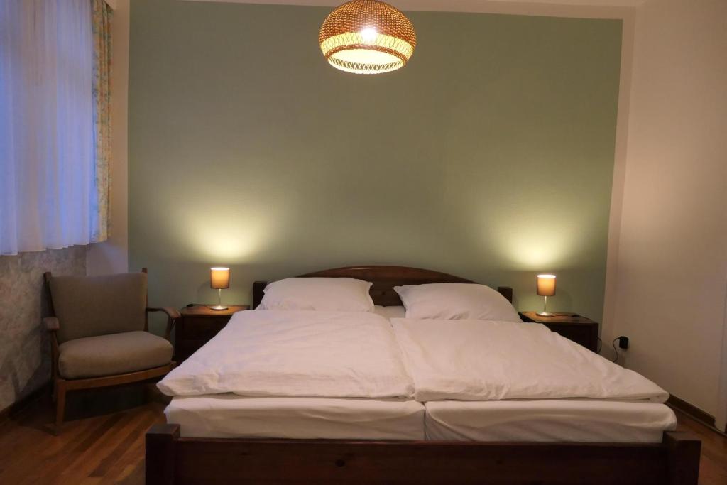 ein Schlafzimmer mit einem Bett, einem Stuhl und einer Lampe in der Unterkunft Malerhaus Einbeck in Einbeck