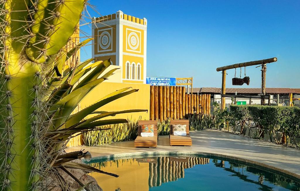 a swimming pool in front of a building with a clock tower at Volantes do Sertão - Ecoville in Piranhas