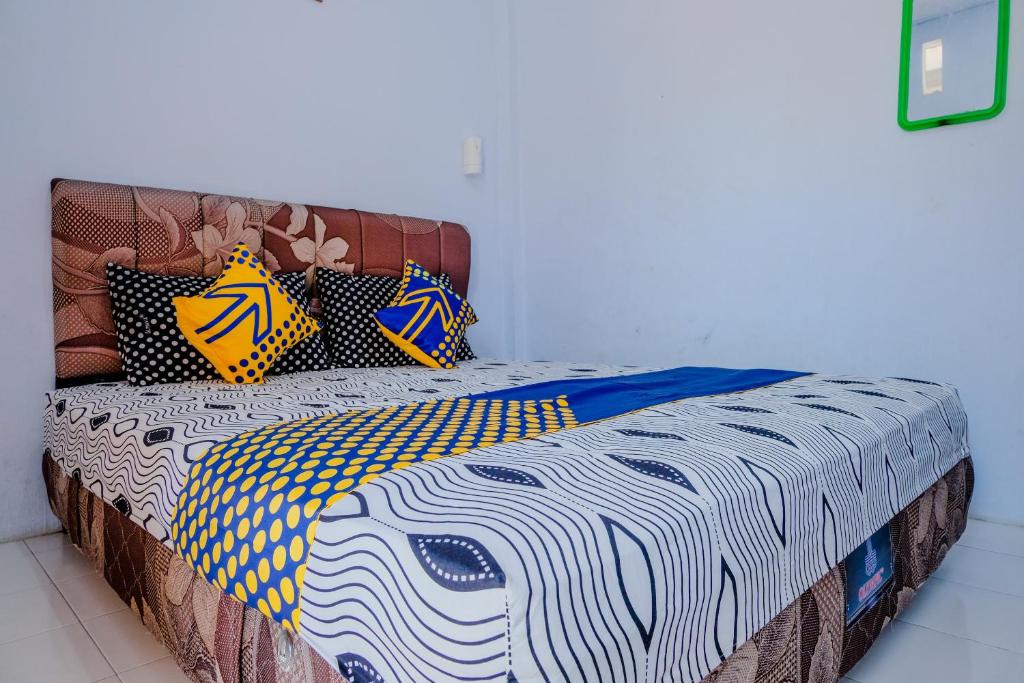 uma cama com almofadas coloridas num quarto em SPOT ON 1958 Asembagus Family em Situbondo