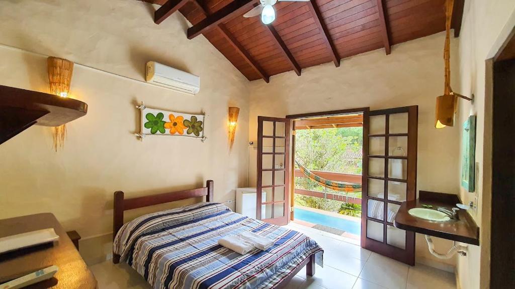a bedroom with a bed and a bathroom with a sink at Hotel e Pousada Canto Mágico in Maresias
