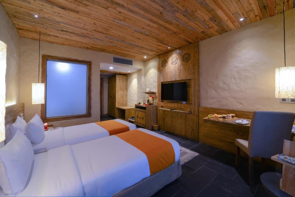 a hotel room with a large bed and a television at Sarangkot Mountain Lodge in Pokhara