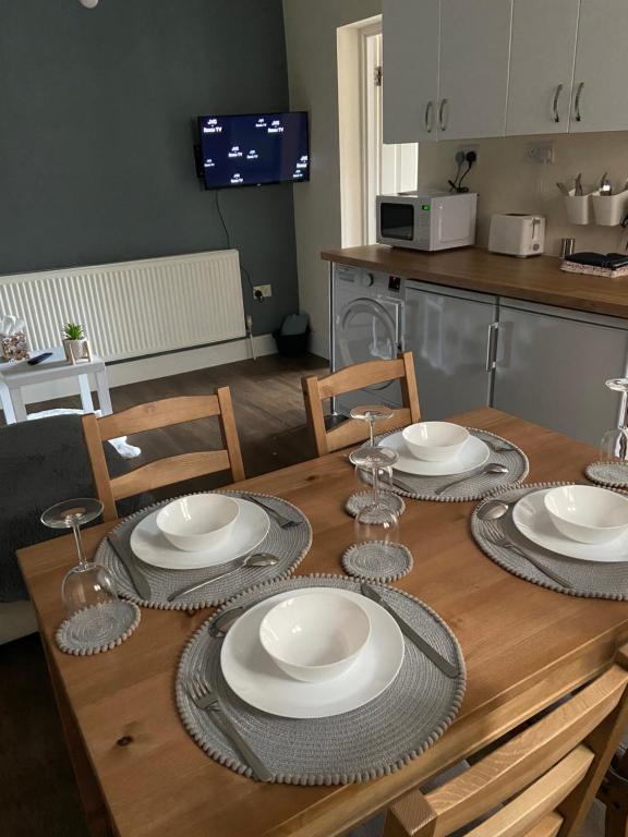 a wooden table with plates and wine glasses on it at 2bed apartment free parking in Oxford