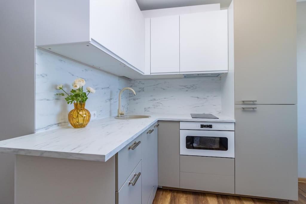 a white kitchen with a vase of flowers on the counter at convenient and comfortable accommodation in Tallinn