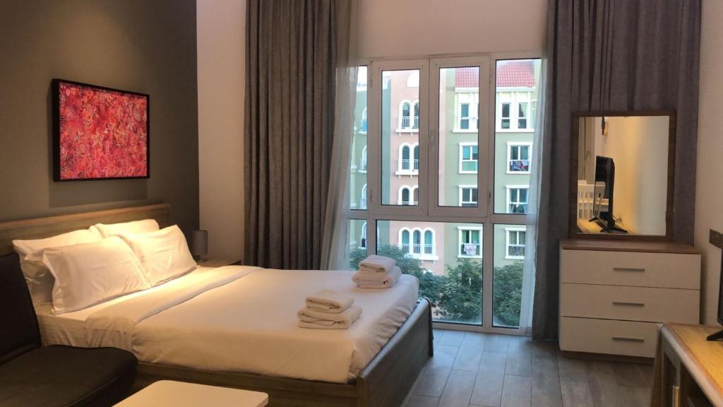 a bedroom with a bed and a large window at Upgraded studio close to Metro in Dubai