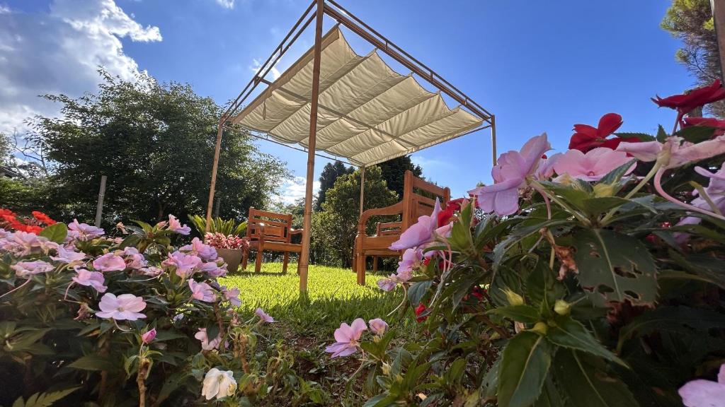 einen Pavillon und Stühle in einem Garten mit Blumen in der Unterkunft Pousada Flor de Lua Monte Verde in Monte Verde