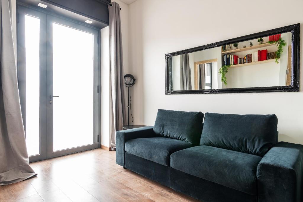 a living room with a blue couch and a mirror at AirLoft 3 confort vicino a Rho Fiera in Rho