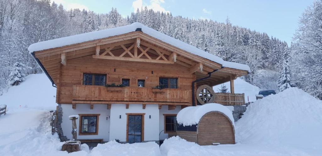 eine Blockhütte im Schnee mit schneebedeckten Bäumen in der Unterkunft Riedlfeld Chalet in Dienten am Hochkönig