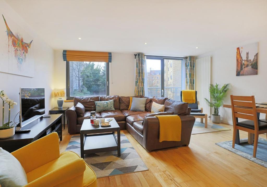 a living room with a brown leather couch and chairs at The East London Residence in Edinburgh