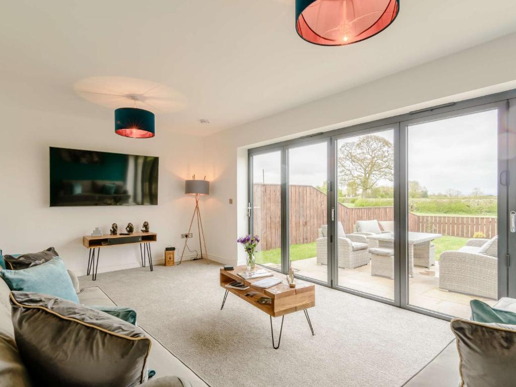 uma sala de estar com portas de vidro deslizantes e uma mesa em 4 bed in Thirsk 82823 em Carthorpe