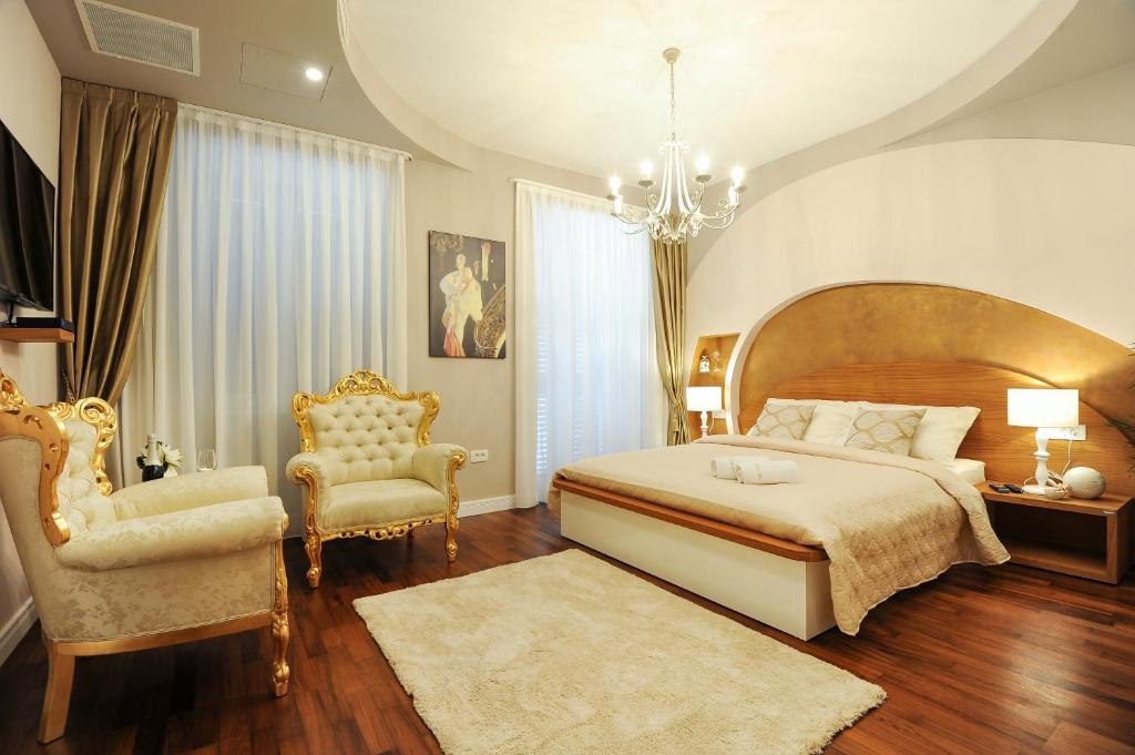 a bedroom with a large bed and two chairs at Silver & Gold Luxury Rooms in Zadar