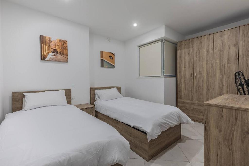 a bedroom with two beds and a counter and a cabinet at Marsaxlokk Fishing Village - Two Bedroom Apartment - 3rd Floor in Marsaxlokk