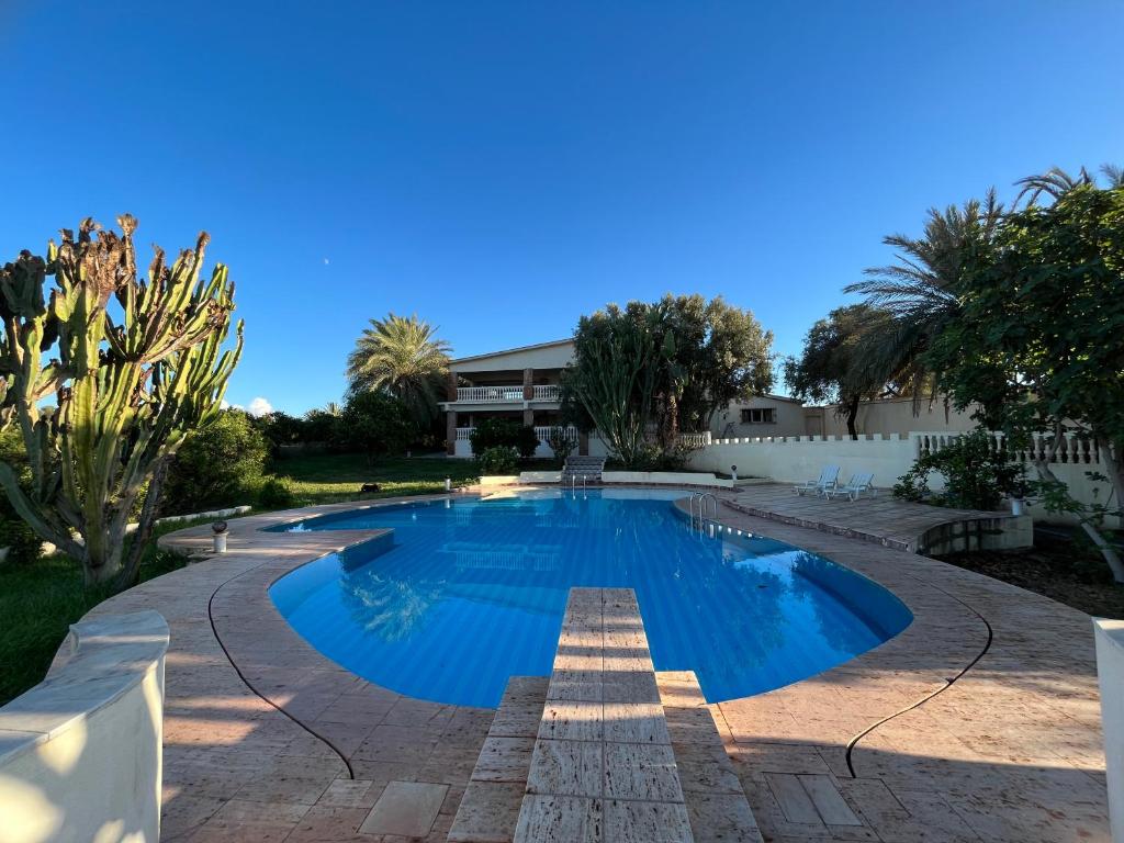 een zwembad met blauw water in een tuin bij Tiguimi Vacances - Oasis Villas, cadre naturel et vue montagne in Agadir