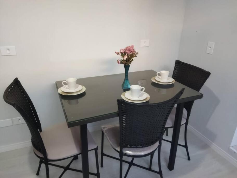 uma mesa de jantar preta com cadeiras e um vaso com flores em Kitnet 1 - próximo ao centro de Jacareí em Jacareí
