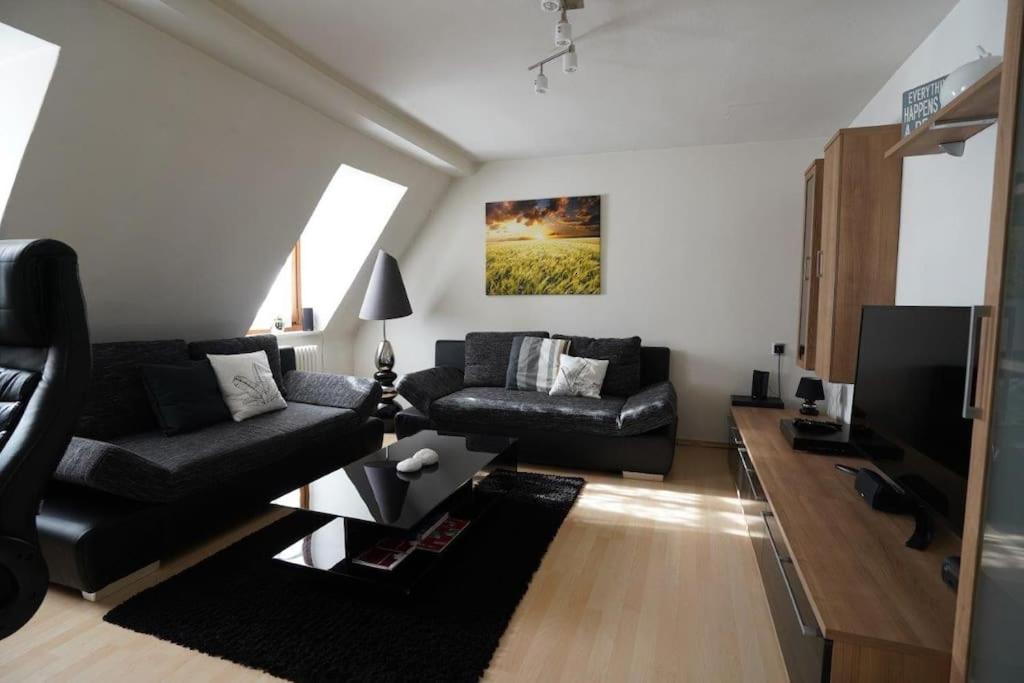a living room with a black couch and a tv at City- Wohnung in Top Lage in Ingolstadt