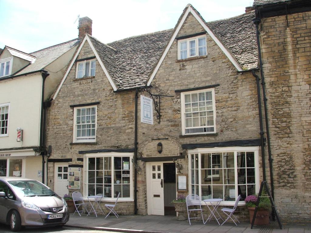 un vieux bâtiment en briques avec des chaises devant lui dans l'établissement The Blenheim Buttery, à Woodstock