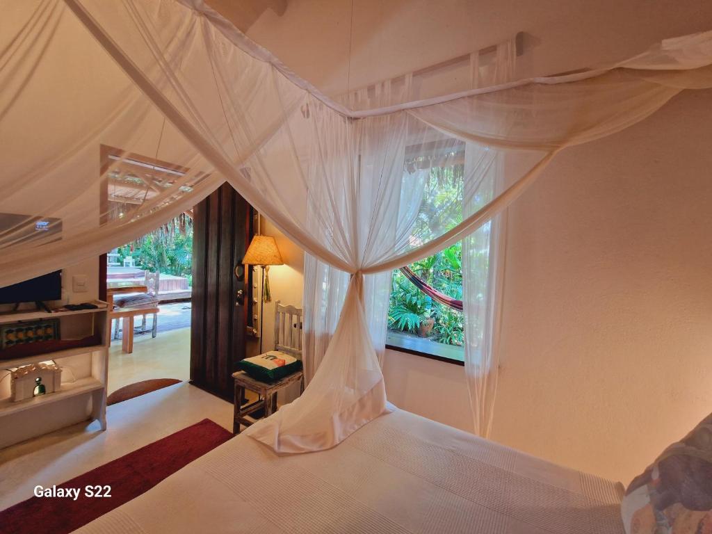 a bedroom with a canopy bed with a window at Mini Casa com Jacuzzi e Piscina in Trancoso