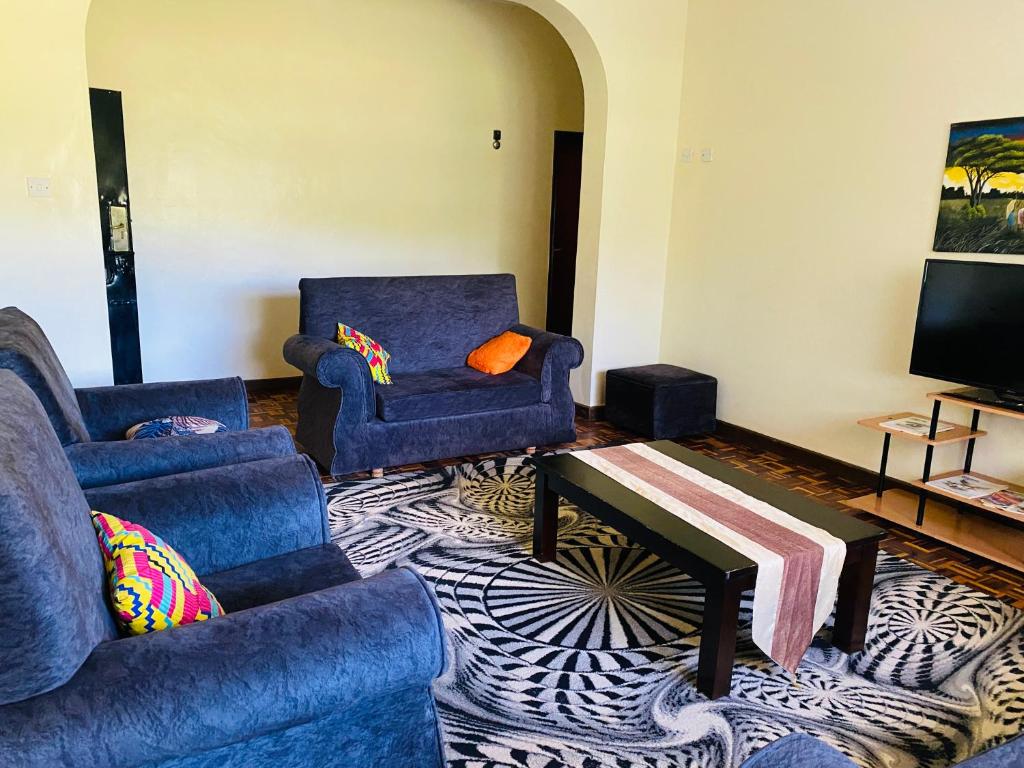 ein Wohnzimmer mit 2 blauen Sofas und einem TV in der Unterkunft Lisa place milimani in Kitale