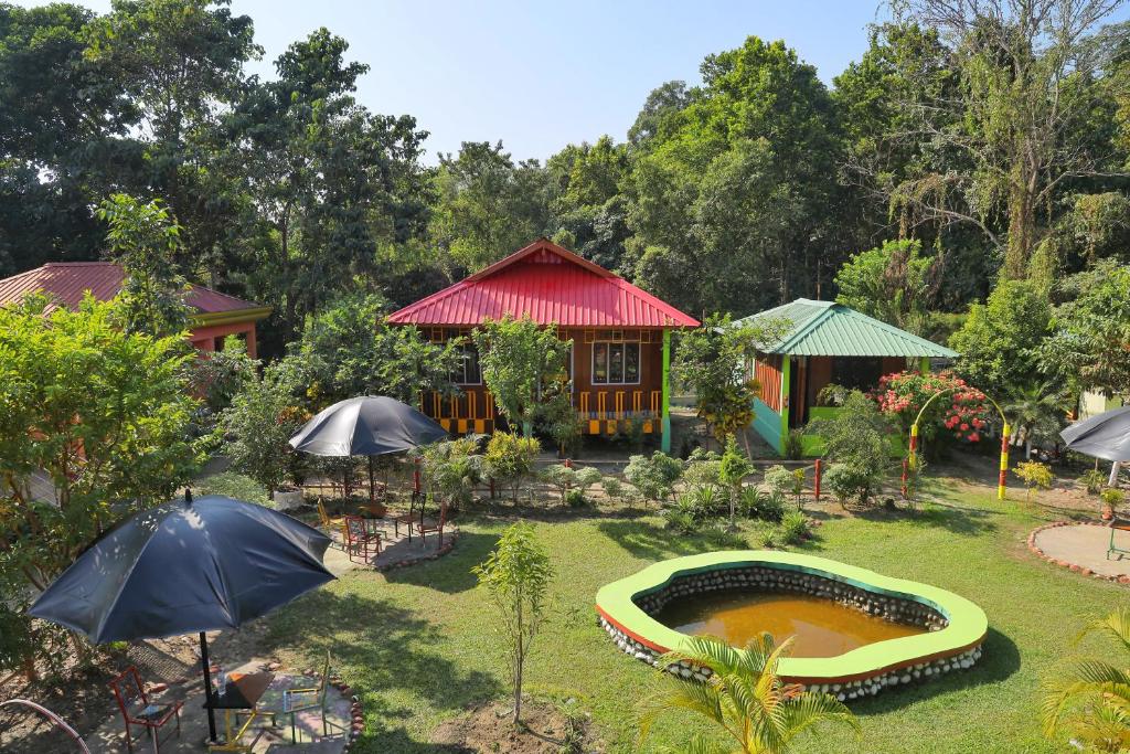 a garden with a house with a pool and umbrellas at Prakriti neerh in Jyoti Gaon