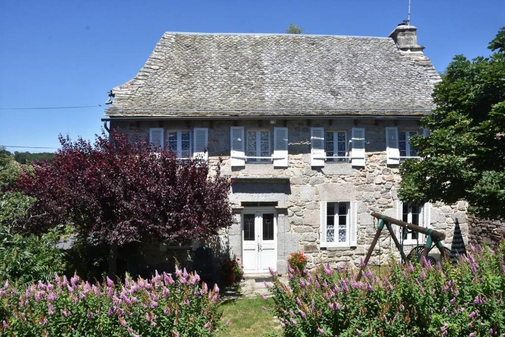 ein altes Steinhaus mit Blumen davor in der Unterkunft Maison paysanne, proche Aubrac in Huparlac