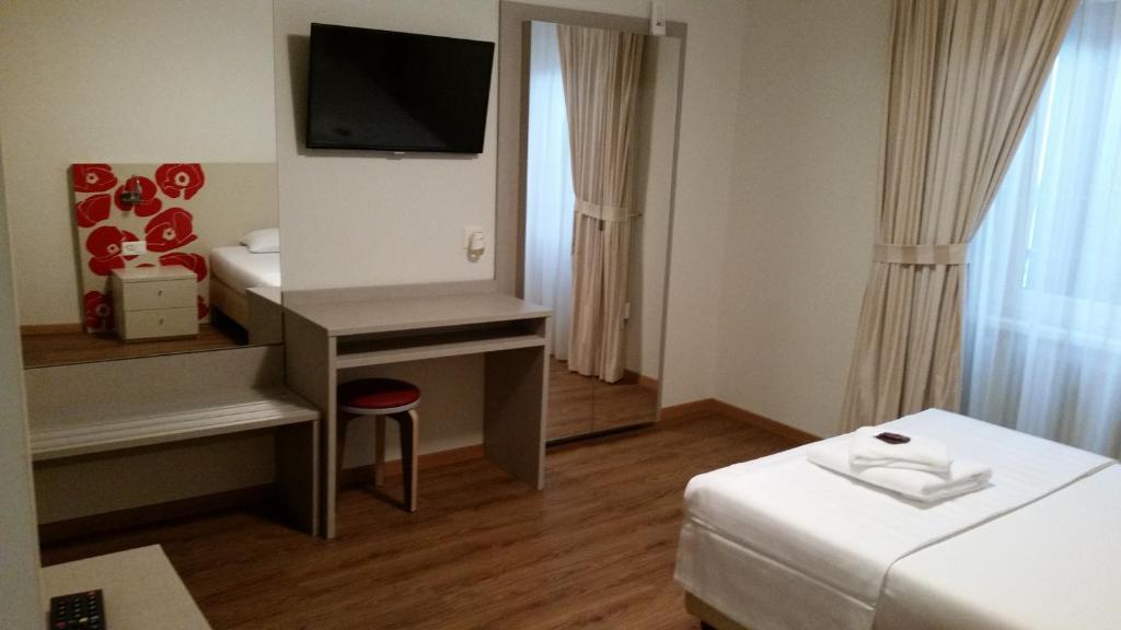 ein Hotelzimmer mit einem Bett und einem Schreibtisch mit einem TV in der Unterkunft Ristorante Stazione con alloggio in Rivera