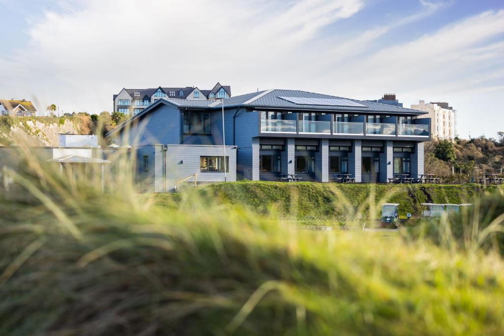 una casa azul frente a un campo de hierba en The Dormy House en Tenby