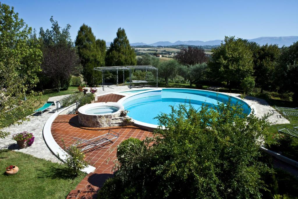 une grande piscine dans un jardin avec une cour en briques dans l'établissement Orchidea - Villa Rita, à Gualdo Cattaneo
