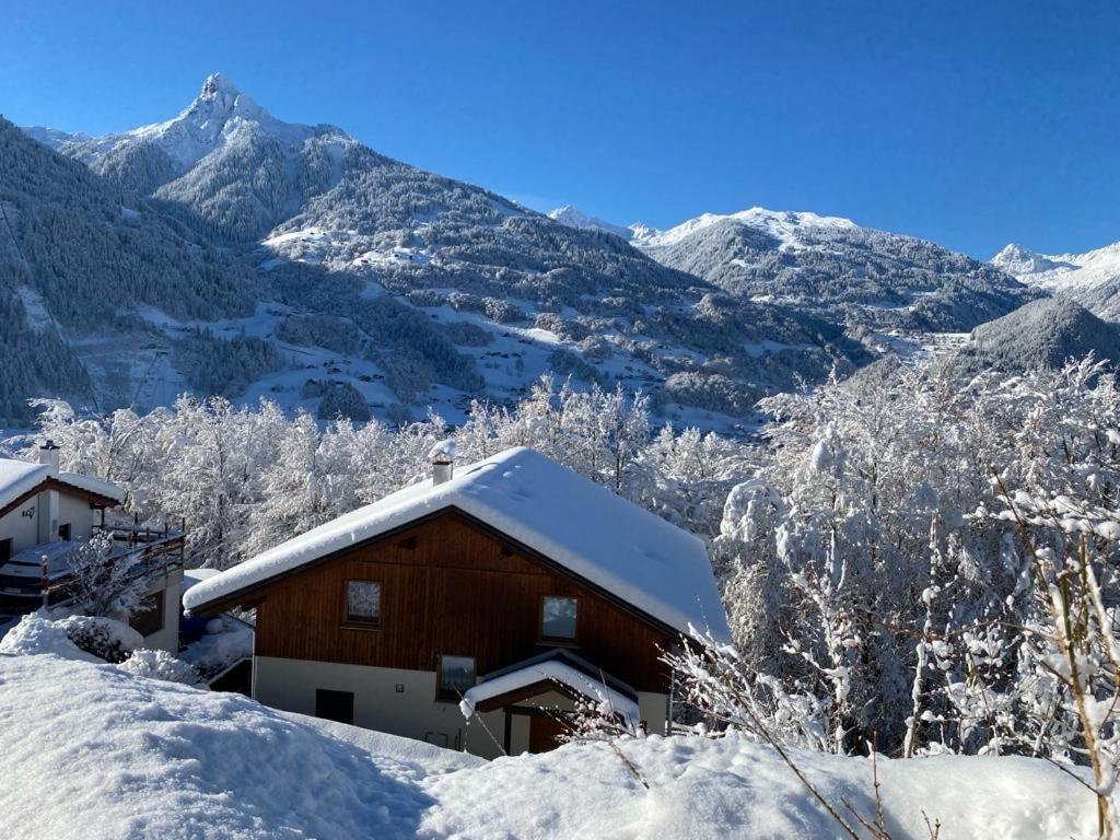 uma casa coberta de neve com montanhas ao fundo em Haus Schröer em Schruns