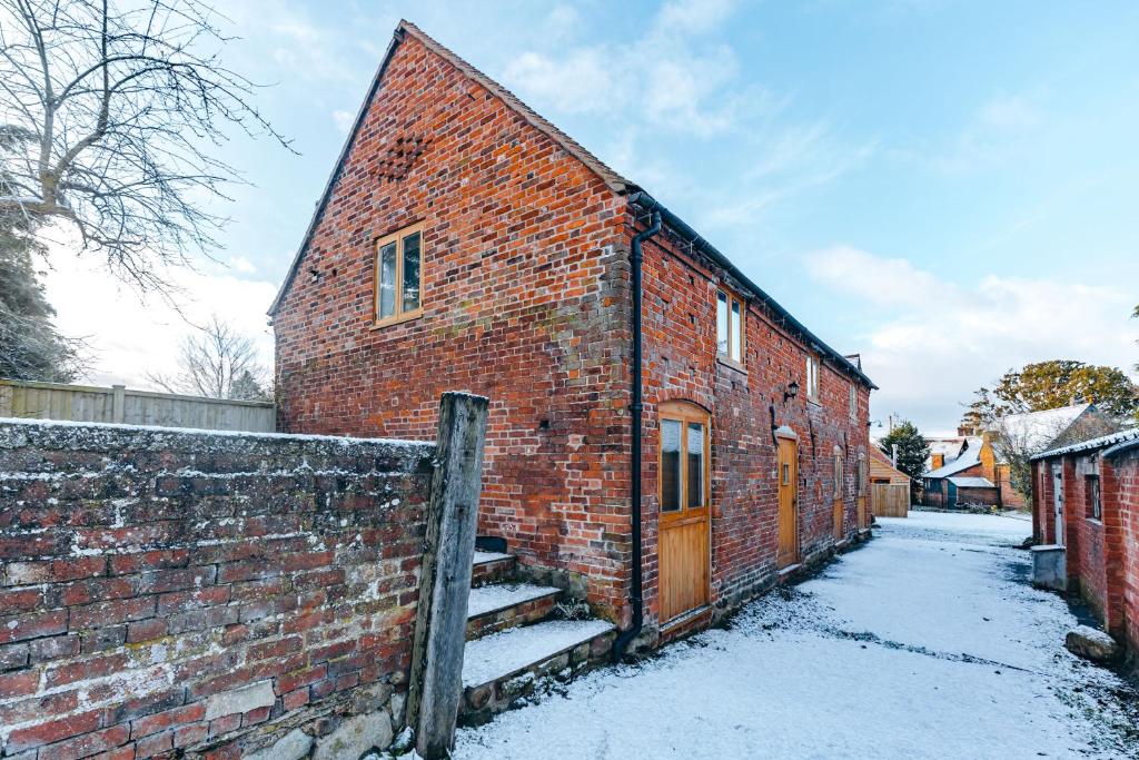 ein altes Backsteingebäude mit Schnee auf dem Boden in der Unterkunft ryton grange hay barn sleeps 6 in Shrewsbury