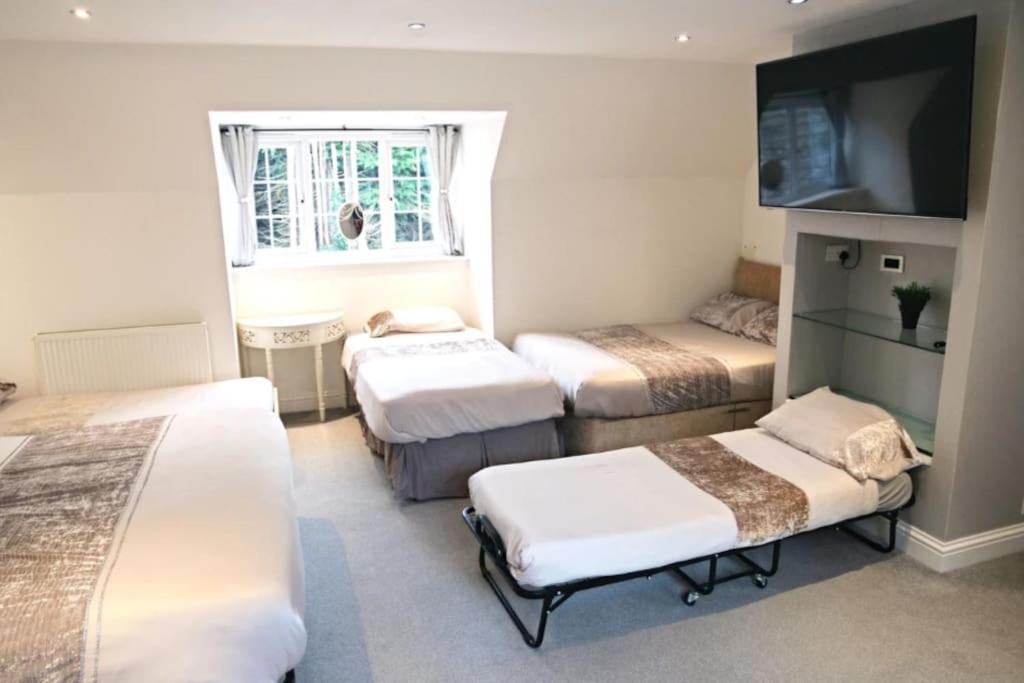 um quarto com três camas e uma televisão em Hen & Stag Retreat Weekend Stay Sleeps 10 to 30 em Thetford