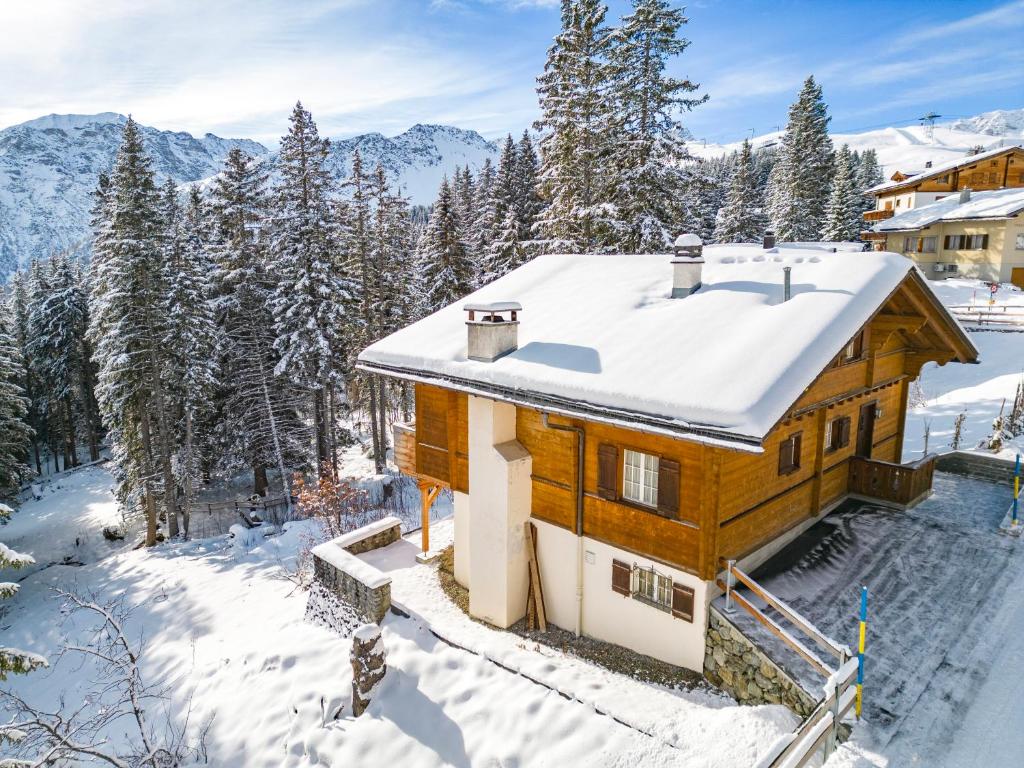 ein Holzhaus mit Schnee auf dem Dach in der Unterkunft Chalet Soldanella by Arosa Holiday in Arosa