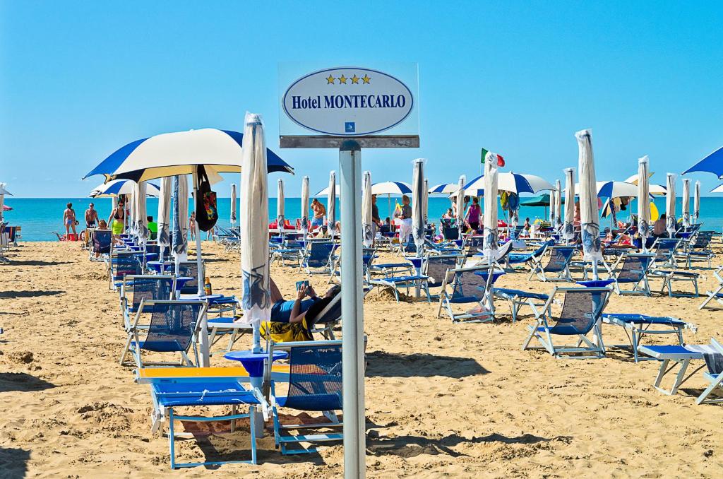 a group of chairs and umbrellas on a beach at Hotel Montecarlo in Bibione