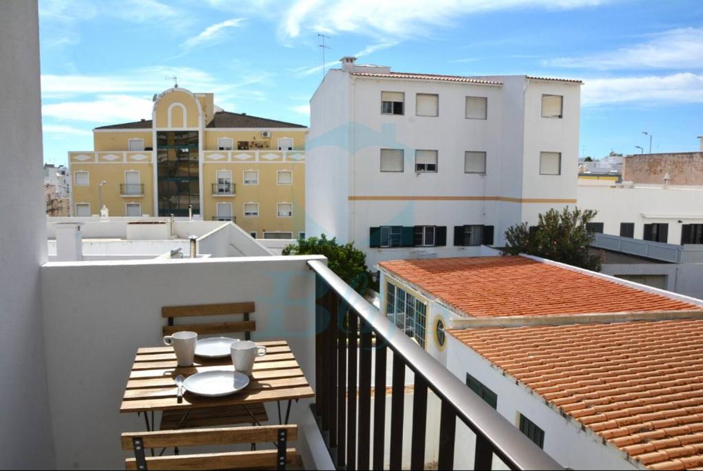 a balcony with a table and chairs on a building at Blife Julya private rooms in Faro