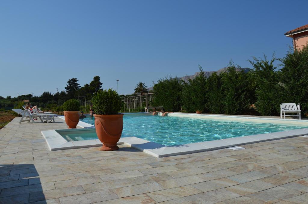 uma piscina com vasos de plantas num pátio em B&B PIANO del RE em Partinico