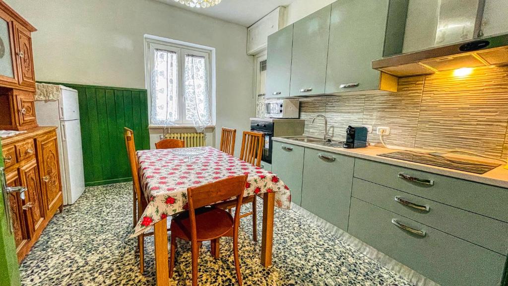 uma cozinha com uma mesa e uma cozinha com armários verdes em Appartamento La Gare - Affitti Brevi Italia em Bardonecchia