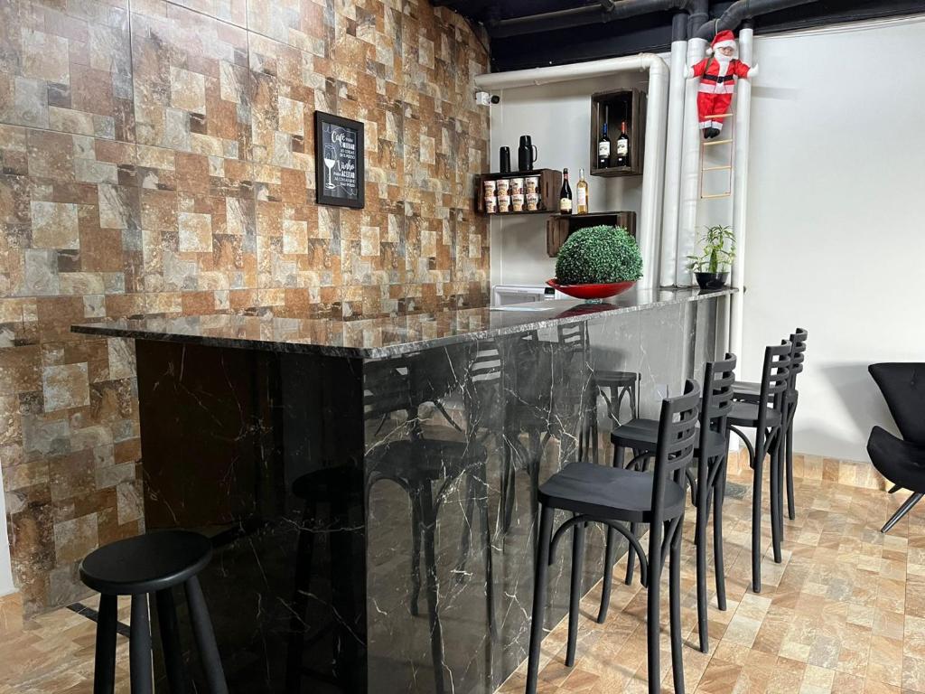 a bar with black stools and a brick wall at Riacho HOTEL in Brasília