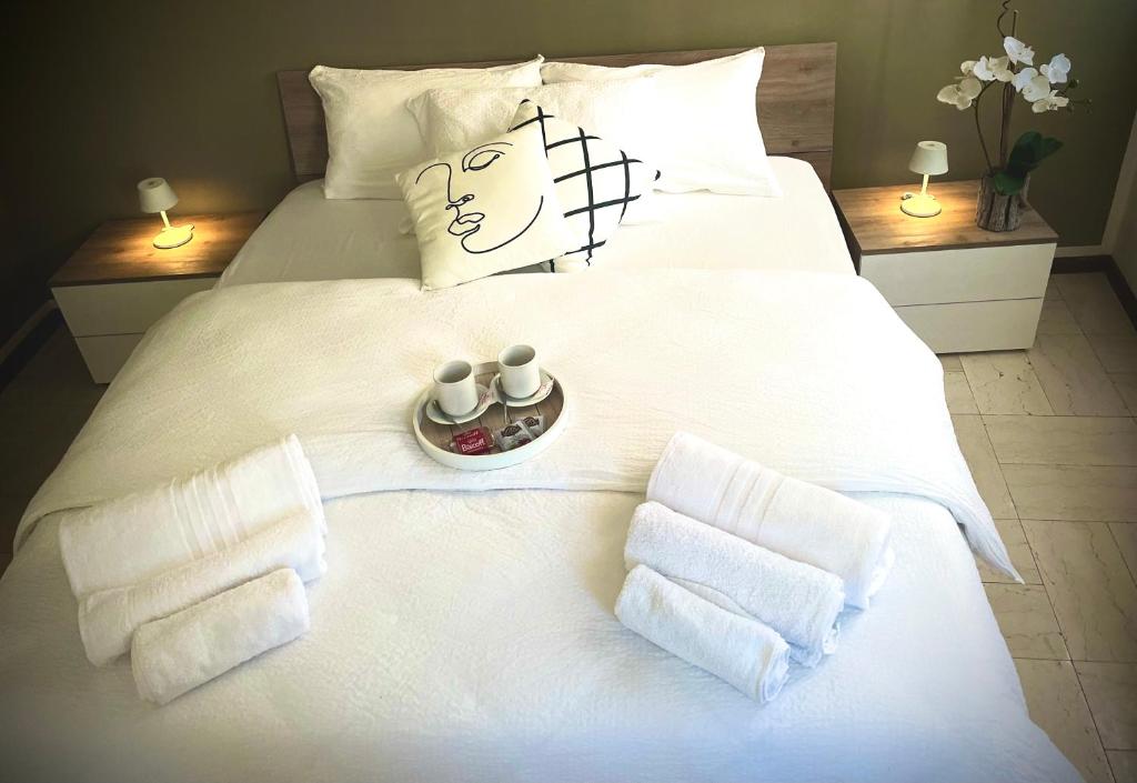 Una cama blanca con dos tazas y toallas. en Civico 31 en Vercelli