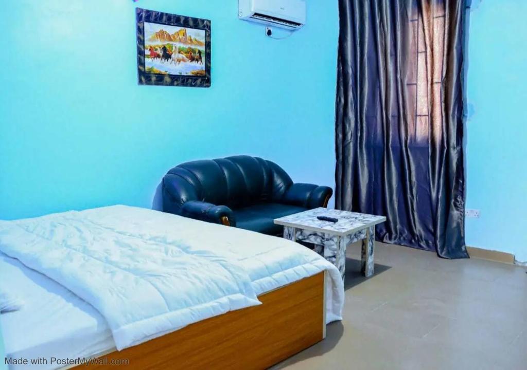a bedroom with a bed and a chair and a table at Elios Hotels in Ughelli