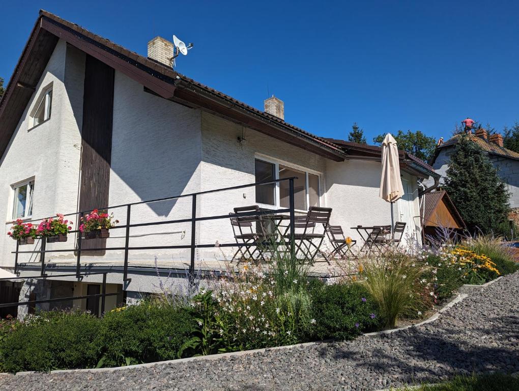 a house with chairs and an umbrella in front of it at Penzion u Vichu in Červená Voda