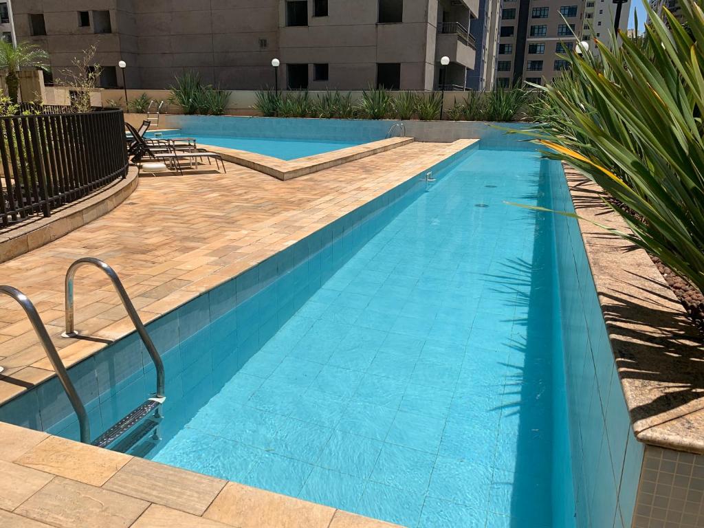 a large swimming pool with blue water in a building at O Lugar! Apto no The Place in São José dos Campos