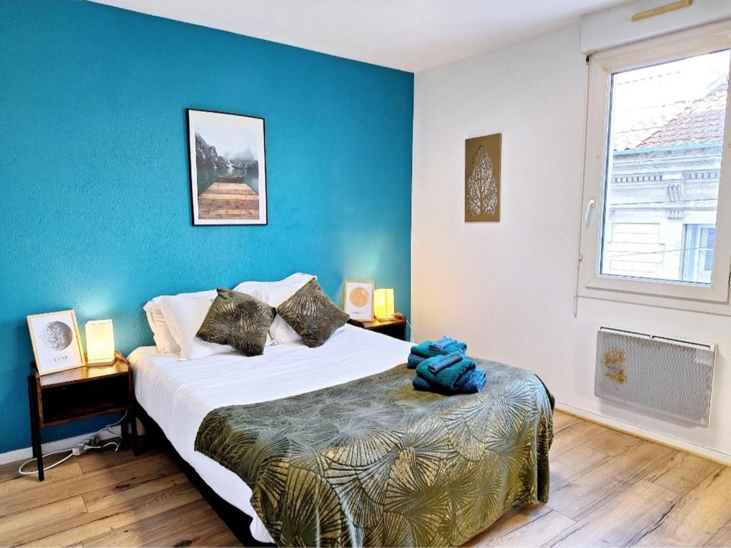 ein Schlafzimmer mit einem großen Bett und einer blauen Wand in der Unterkunft Appartement Cosy Proche Gare - Fibre Optique et Parking in Angoulême