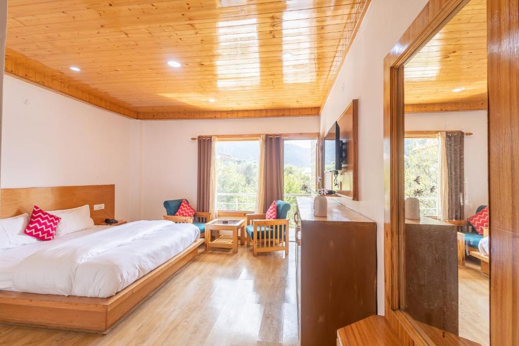 een slaapkamer met een bed, een bureau en stoelen bij Aroha Residency- A Countryside Resort in Manāli