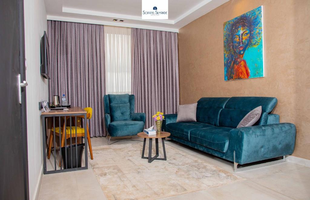 uma sala de estar com um sofá azul e uma cadeira em Sopatel Silmandé em Ouagadougou