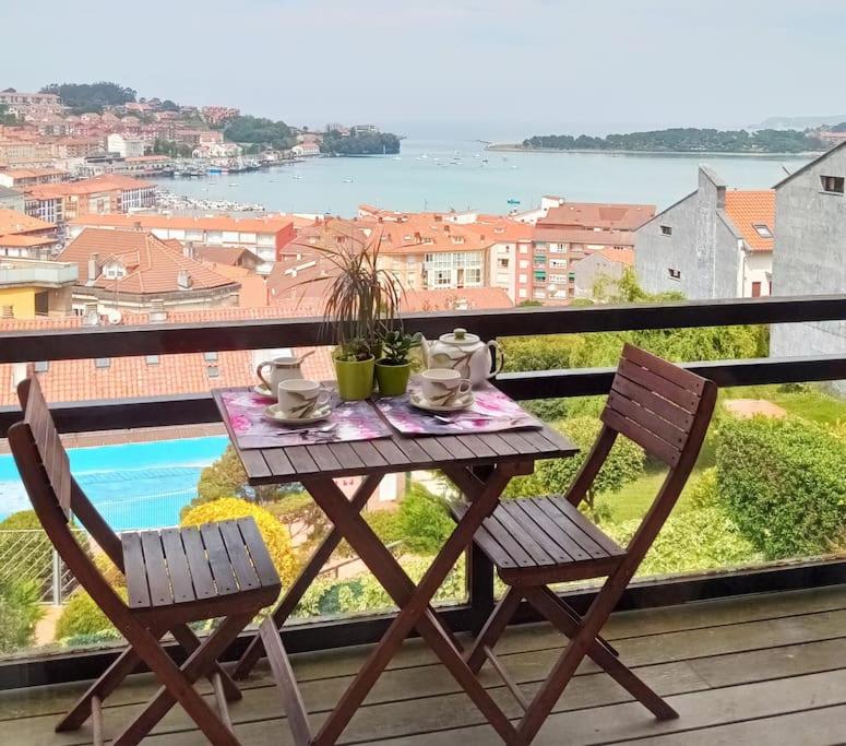 una mesa y sillas en un balcón con vistas en Terraza y piscina con vistas espectaculares al mar Parking cubierto, en San Vicente de la Barquera