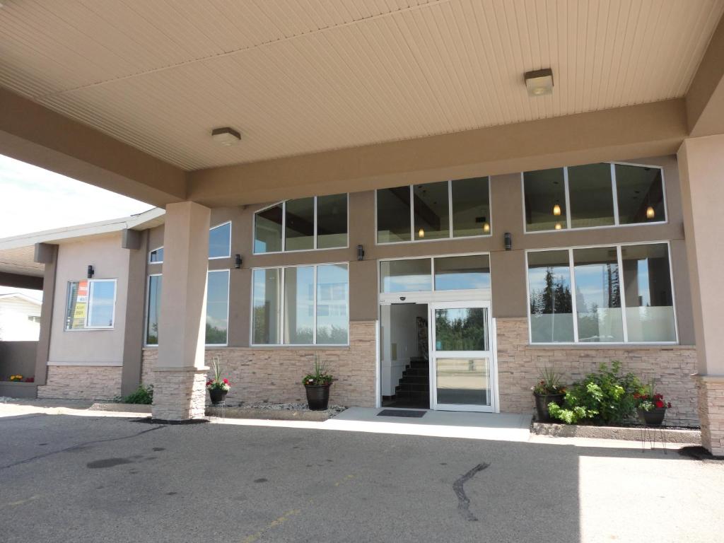 ein großes Gebäude mit großen Fenstern und Blumen auf einem Parkplatz in der Unterkunft South Hill Motor Inn in Red Deer