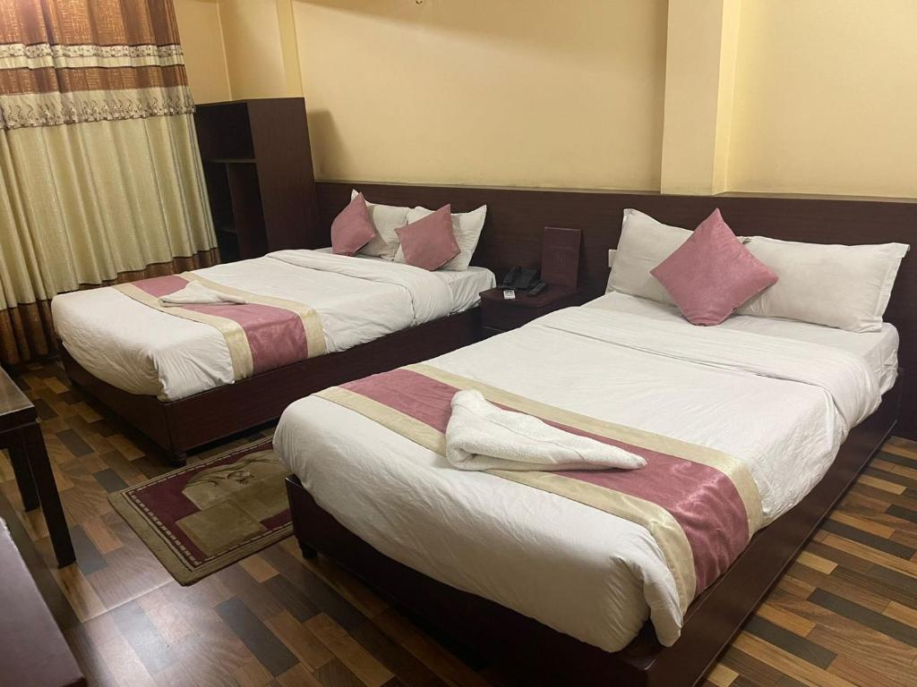 2 camas en una habitación de hotel con almohadas rosas en Rameshworam Hotel, en Katmandú