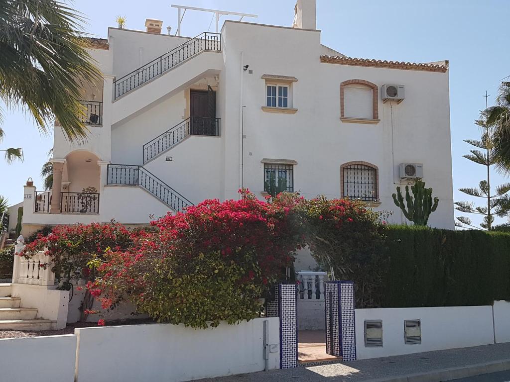 a white house with flowers in front of it at Atico Villamartin 6 sleeps in Villamartin