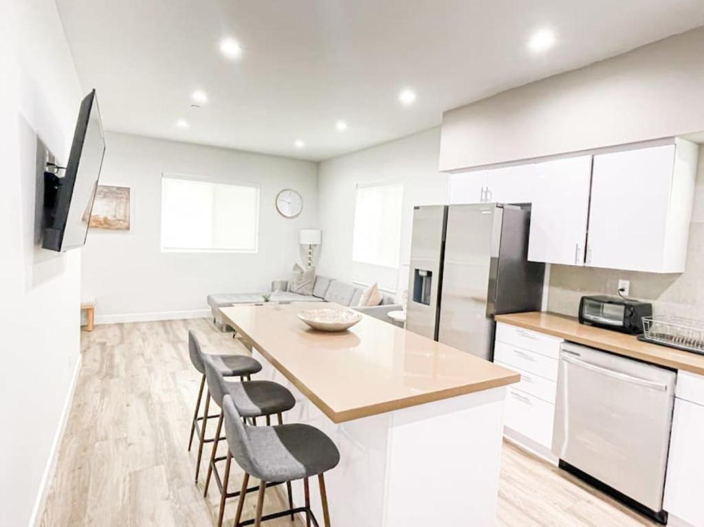 uma cozinha com armários brancos e uma ilha de cozinha com bancos em Stylish Townhouse in Mid City - CR2-CUL em Los Angeles