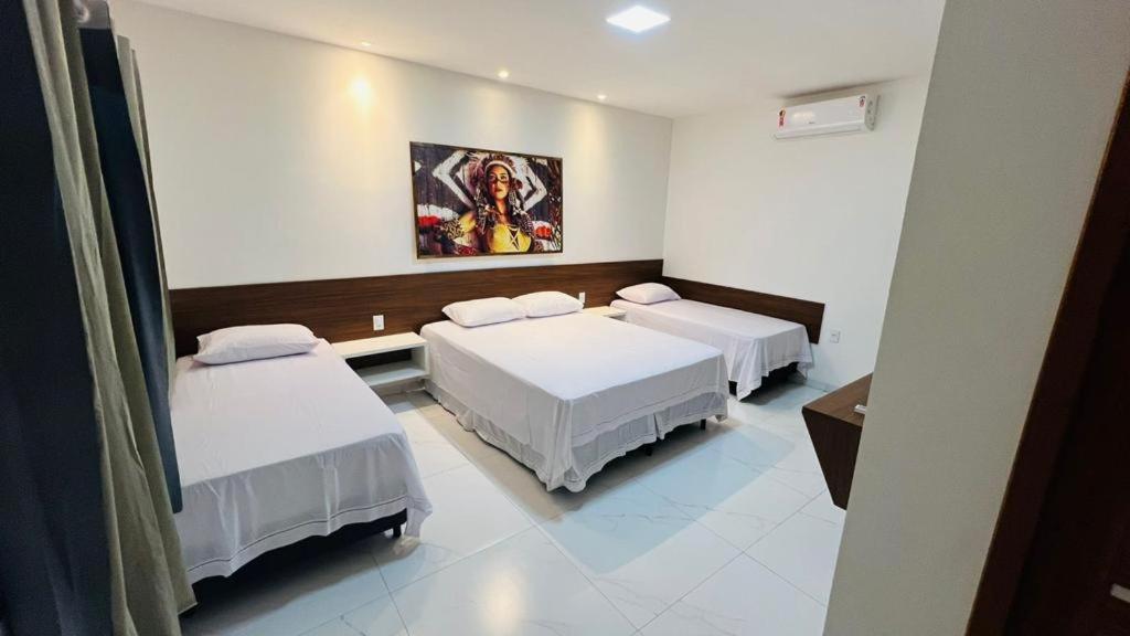um quarto com três camas e um quadro na parede em CHALES TEMATICOS em Belterra