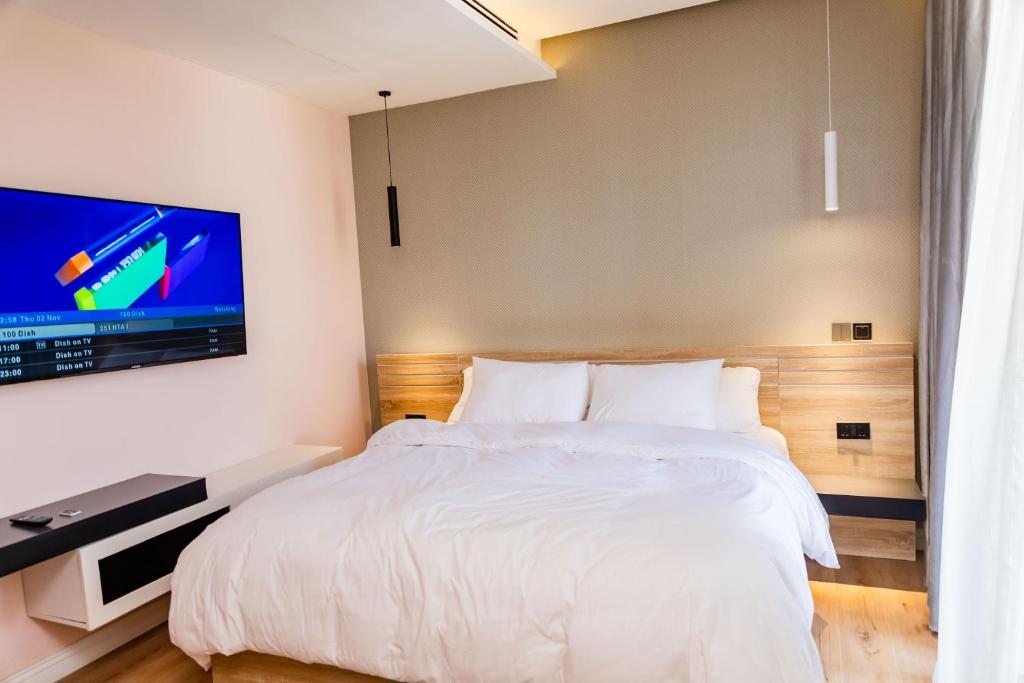 1 dormitorio con 1 cama y TV en la pared en Lakehouse Apartment - Lake Powell - One Bedroom Apartment with Balcony, en Abuja