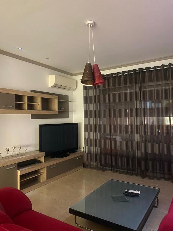een woonkamer met een bank en een televisie bij Emma & Ella Apartment in Tirana